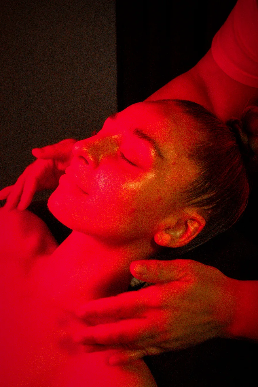 Neck and shoulder release under red light during a POSTURE FIX session at WAJH